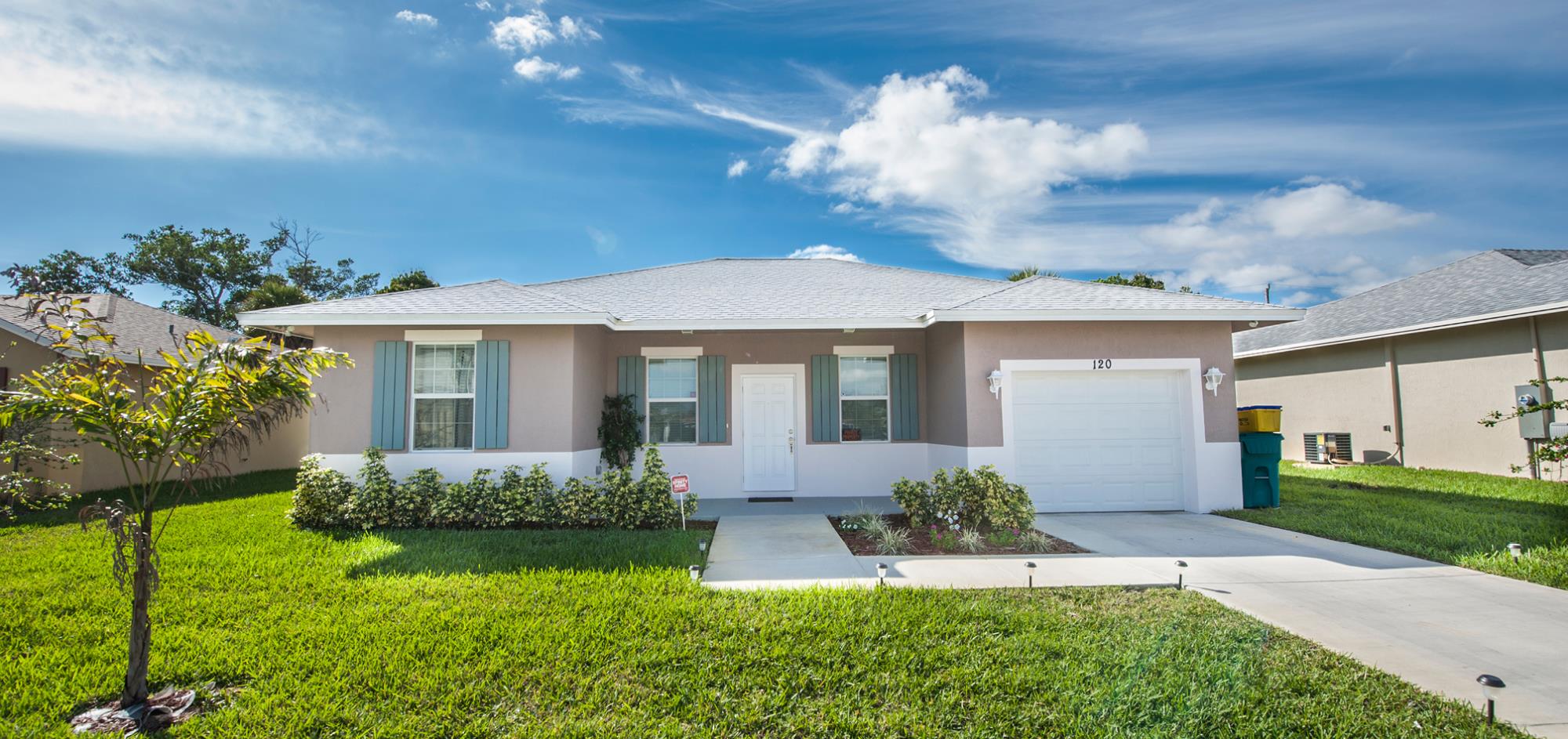 Gray house with white trim, One story, one car garage with a grass lawn