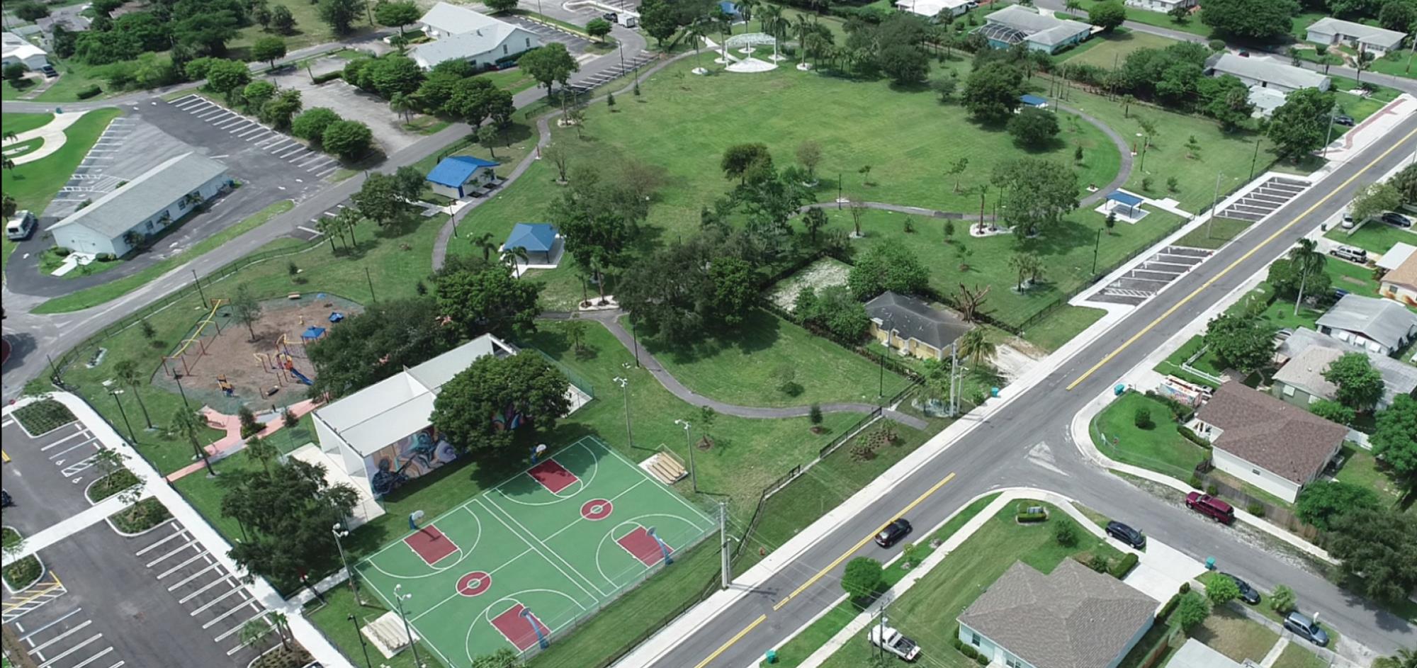 Aerial view from east of whole park featuring playground, pavilions, walking paths, basketball courts and amphitheater