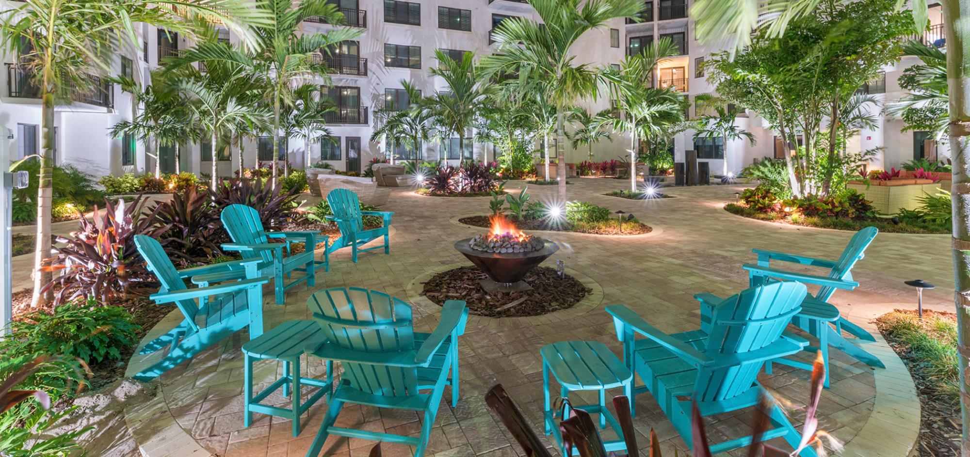 Adirondack Chairs around a fire fit with Palm trees in background