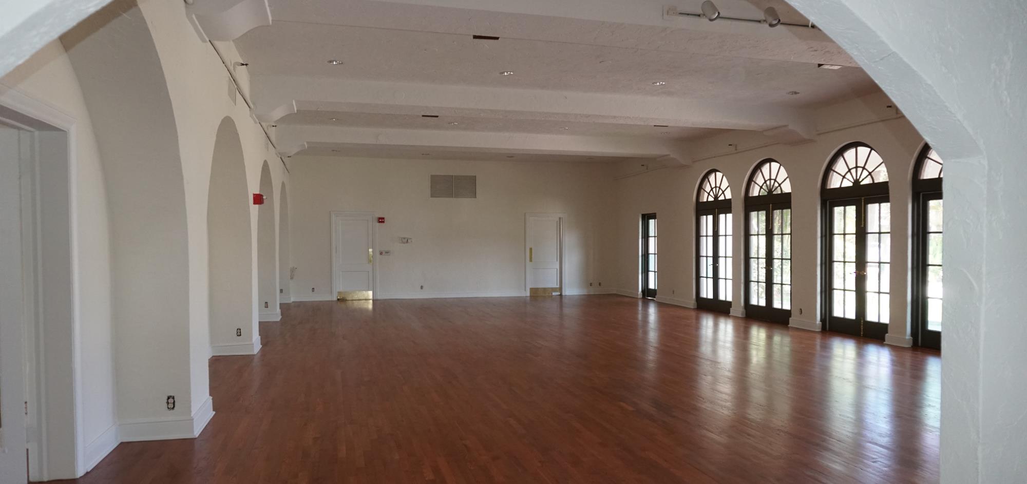 East Room featuring refinished wood floors and arched entries and five French doors