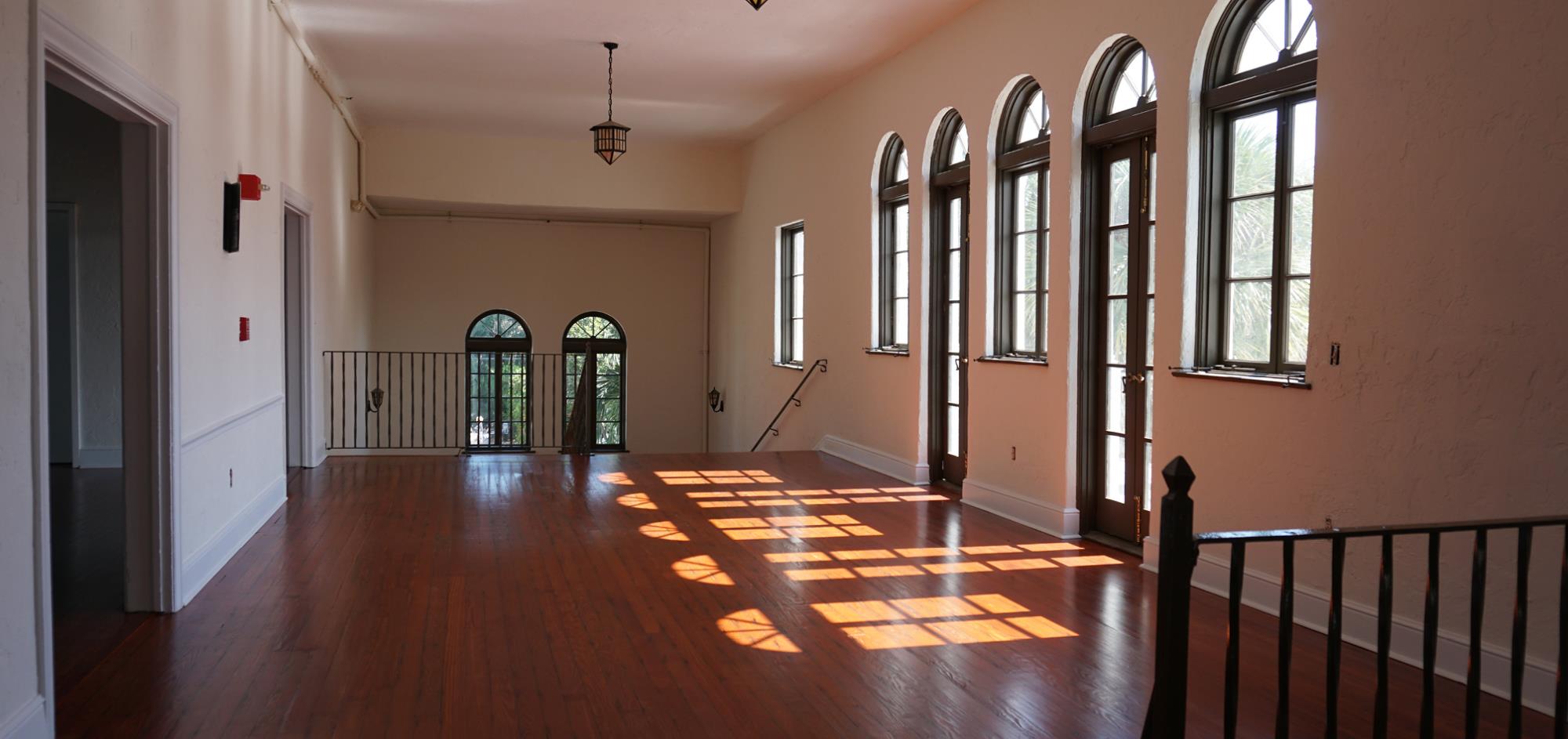 Foyer of upstairs ballroom featuring arched windows and one French door to balcony