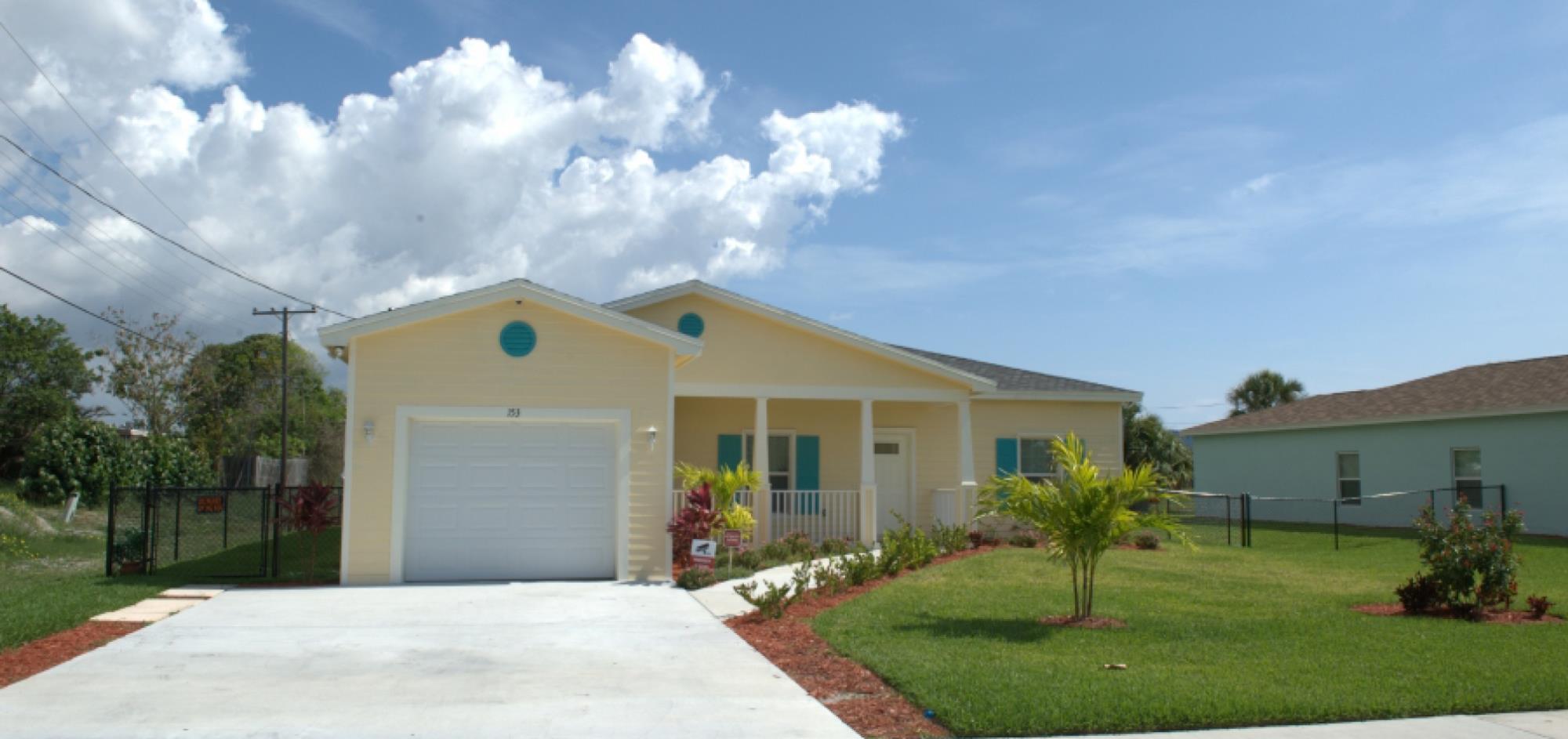 Yellow House with one car garage and white trim with grass lawn