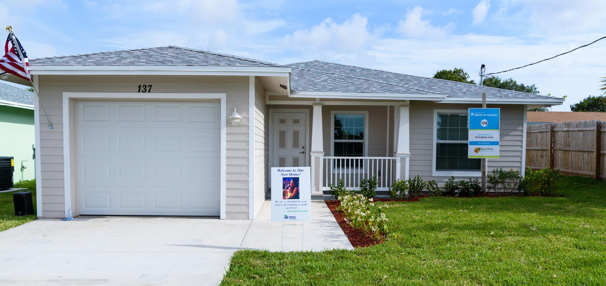 Beige house with one car garage and white trim with grass lawn