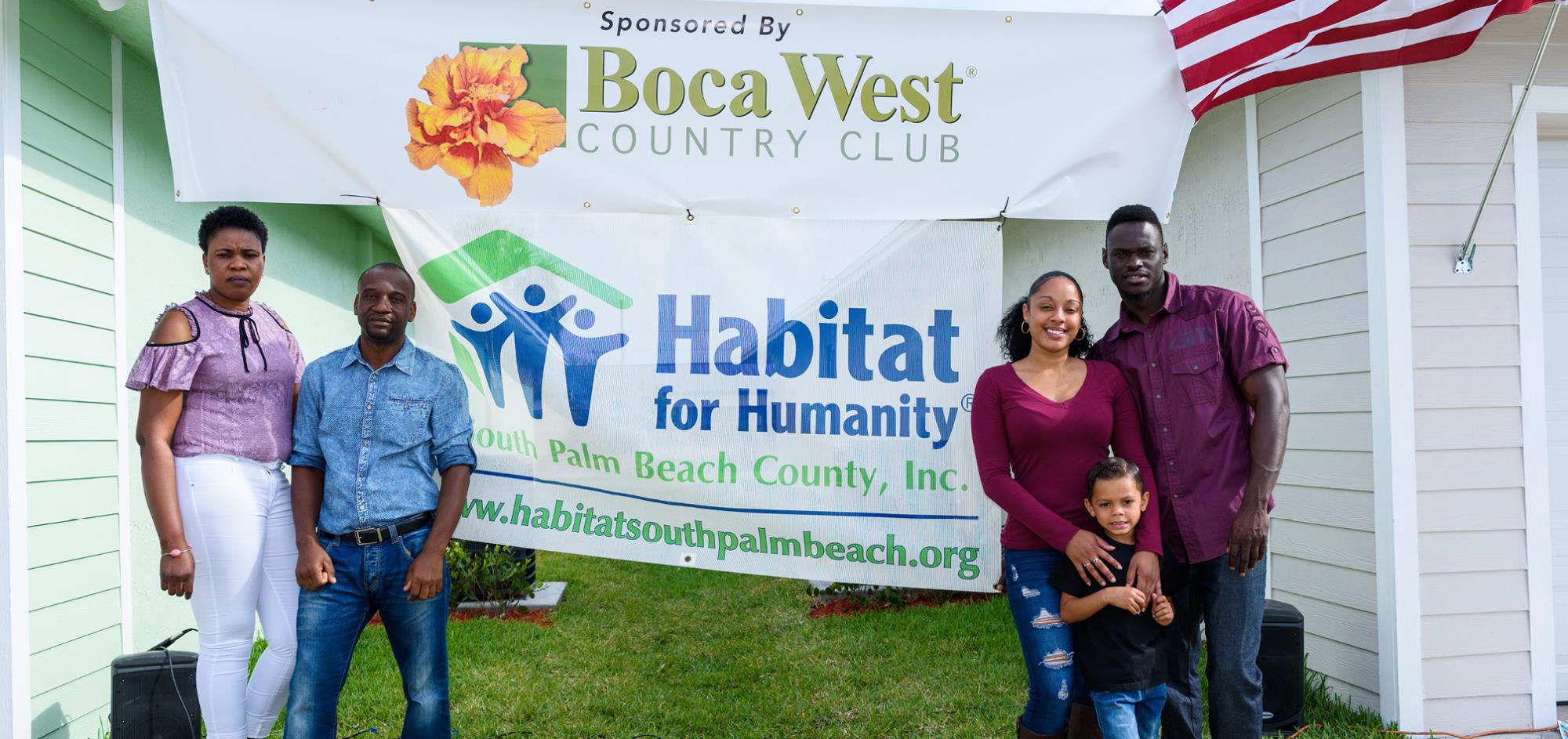 Two families separated by a banner from Habitat for Humanity