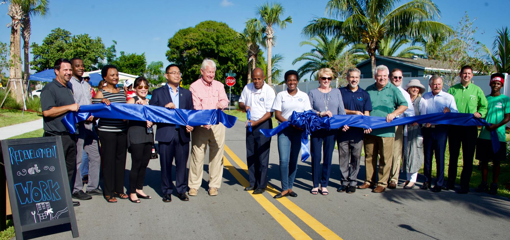 Group photo with City Commissioners, City Manager, CRA Director holding blue ribbon for the completed roadway improvement project